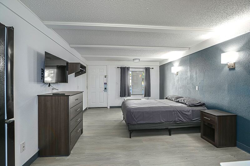 Furnished studio with bed, dresser and TV wall